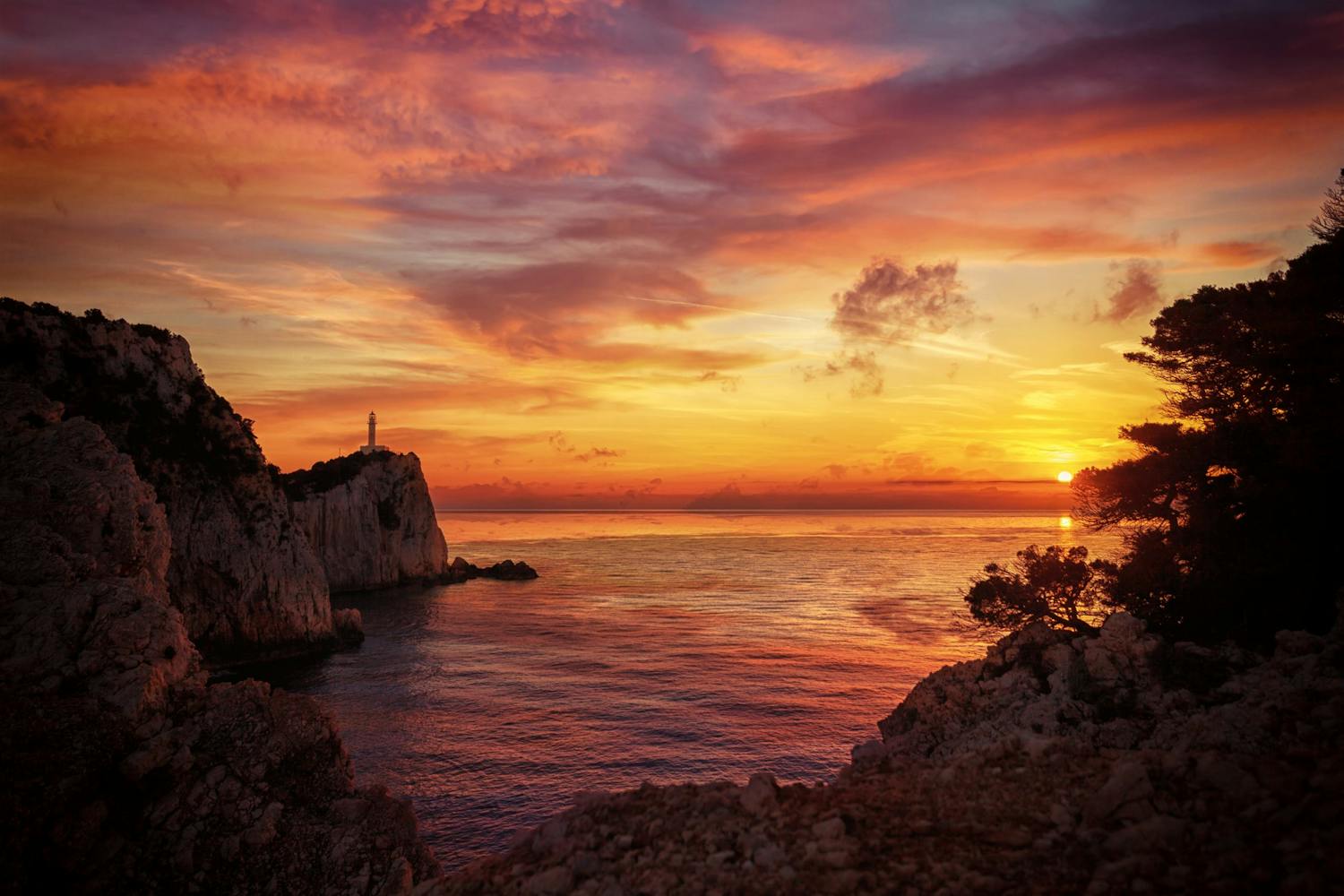 Solnedgång över havet med fyrtorn och klippor